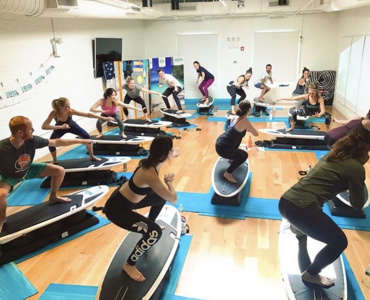 workout room with people standing on surfboards