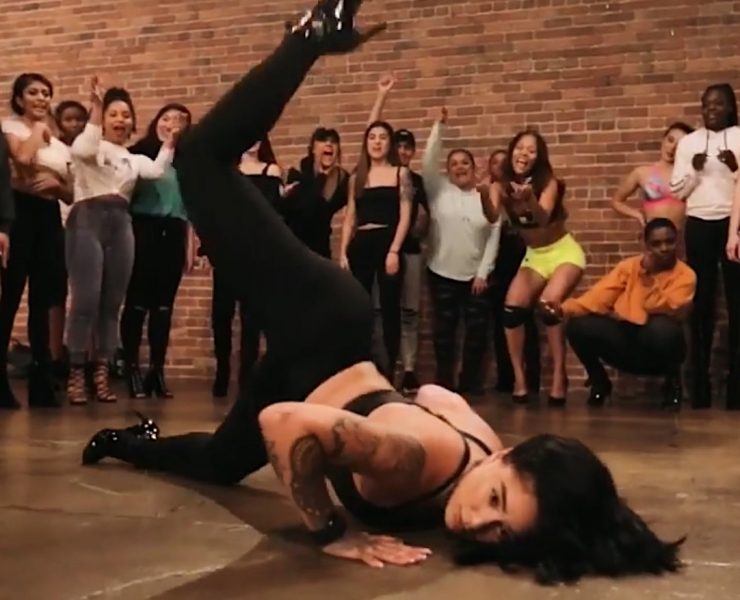 woman on floor dancing with crowd around her cheering