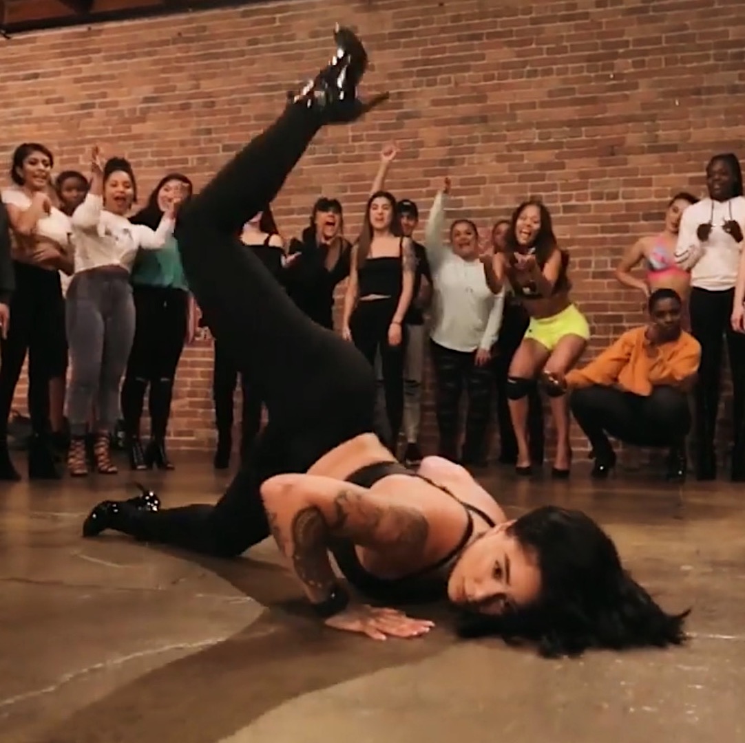 woman on floor dancing with crowd around her cheering