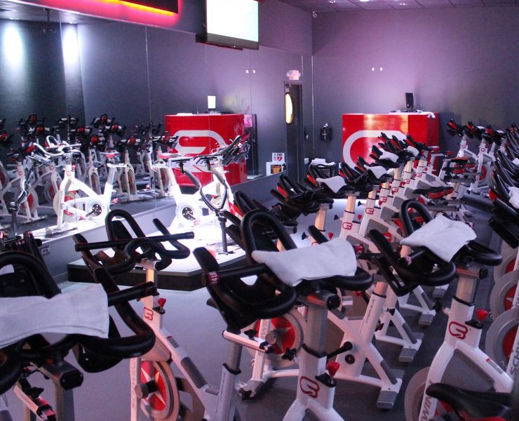 inside the cyclebar studio. Multiple white spin bikes and a red neon cyclebar sign