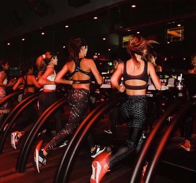 women running on the treadmill in a dark room with red lights