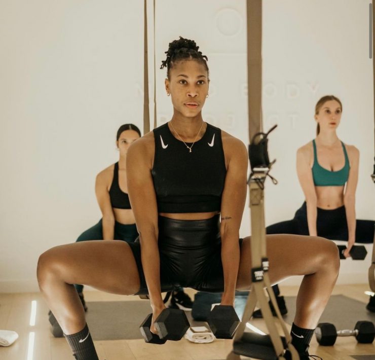 Workout class with woman in black squatting with weights