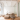 Interior of a yoga studio lobby. All white, wooden floors, brown couch and a large hanging crystal.